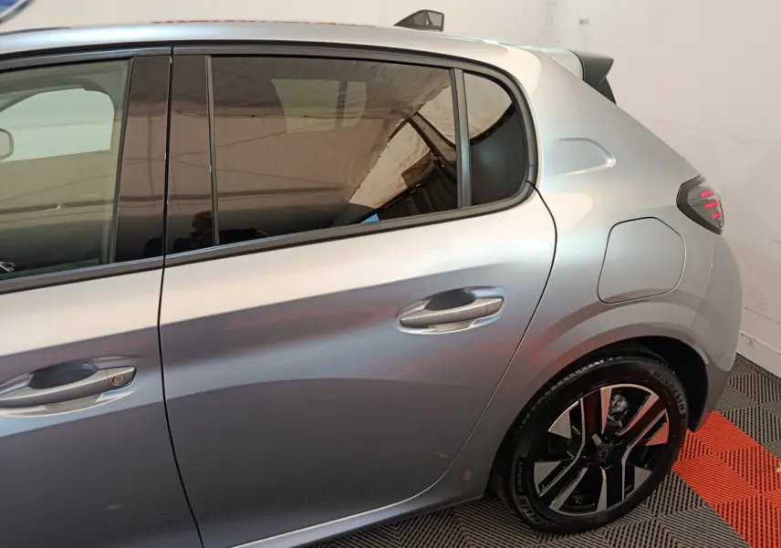 Profil côté droit de la Peugeot 208 gris clair 2025, mettant en valeur la porte arrière et la jante au design moderne.
