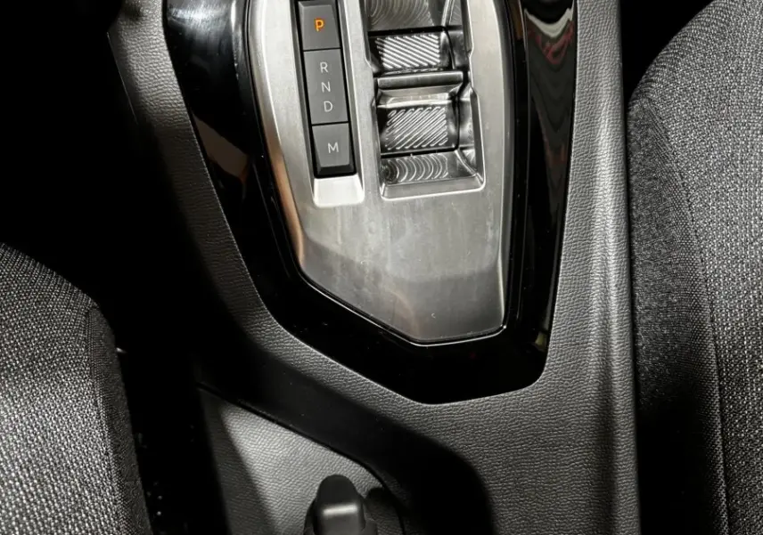 Gros plan sur la console centrale de la Peugeot 208 Hybrid 110, avec la commande de boîte automatique et frein à main manuel.