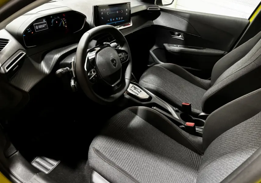 Vue intérieure côté conducteur de la Peugeot 208 Hybrid jaune, avec tableau de bord numérique et écran tactile central.
