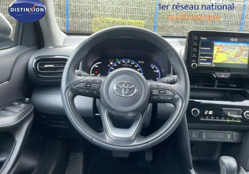 Vue intérieure centrée sur le volant noir de la Toyota Yaris Cross 2024, avec tableau de bord digital et écran GPS visible.