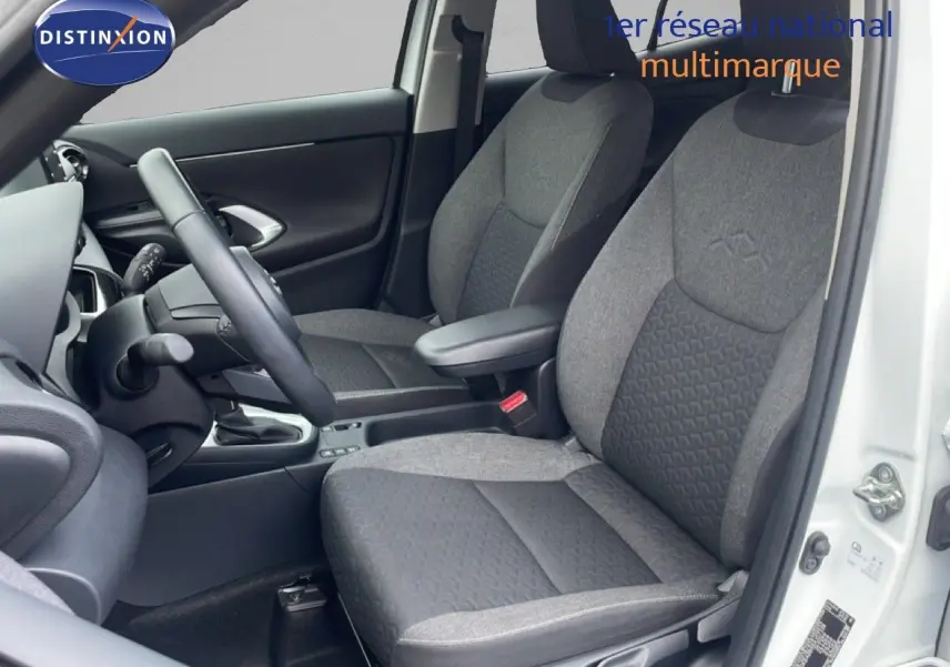 Vue intérieure côté conducteur de la Toyota Yaris Cross Hybrid 2024 avec sièges tissu gris et volant noir.