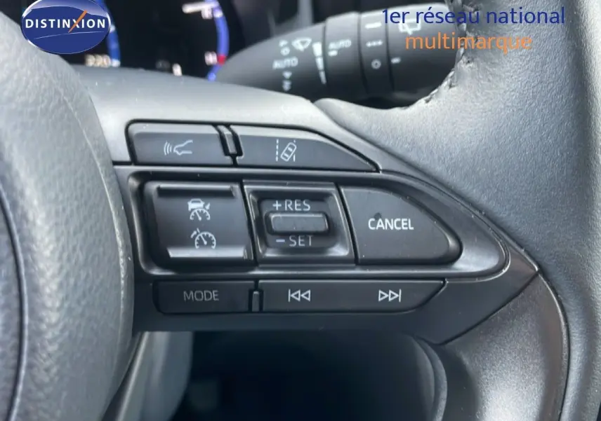 Gros plan sur les commandes au volant côté droit de la Toyota Yaris Cross Hybrid blanche, avec régulateur de vitesse et fonctions multimédia.