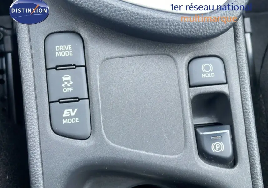 Gros plan sur la console centrale grise de la Toyota Yaris Cross Hybrid 2024, montrant les boutons Drive Mode, EV Mode et frein de stationnement.