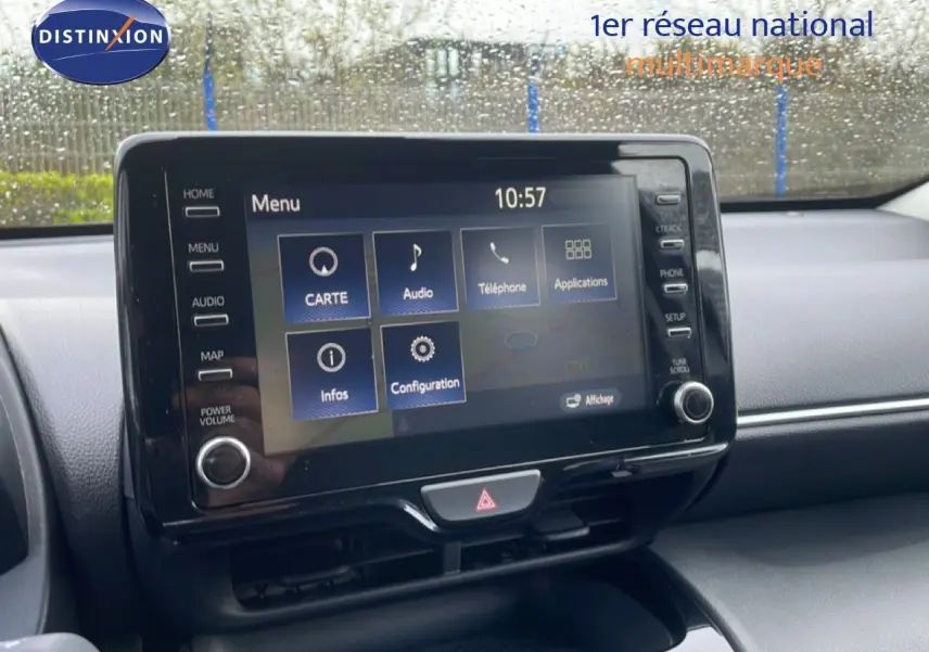 Écran tactile central de la Toyota Yaris Cross Hybrid blanc, vue intérieure du tableau de bord sous la pluie.