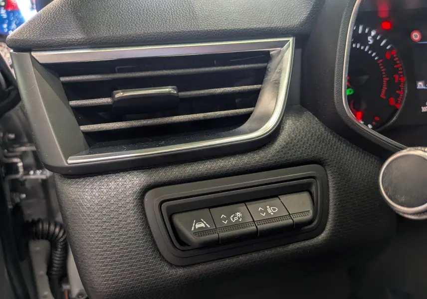 Gros plan sur les commandes d’aide à la conduite à gauche du volant dans l’habitacle gris platine d’une Renault Clio V TCe 90 auto-école.