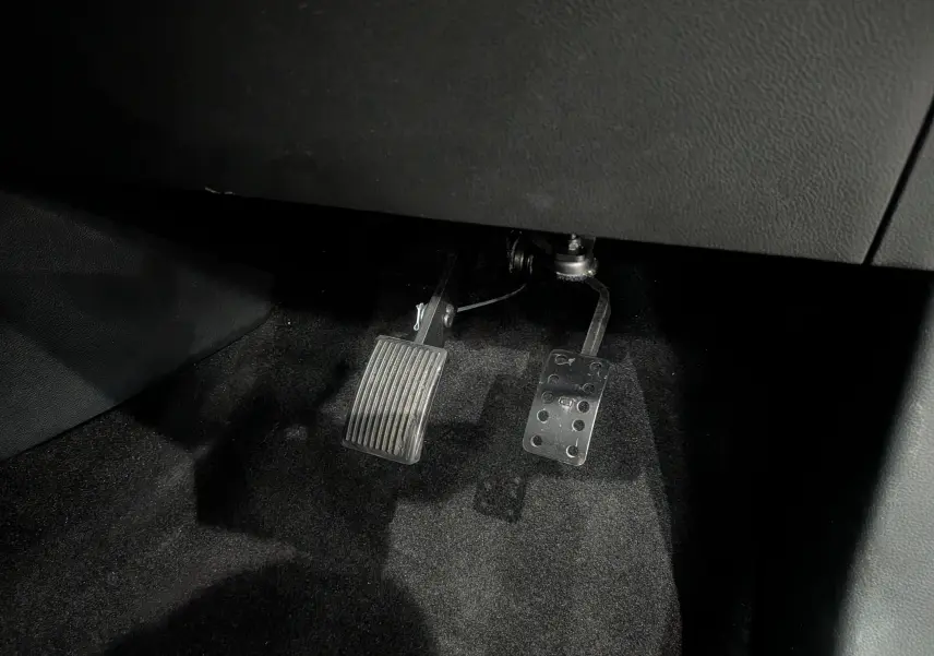 Gros plan sur les pédales d’accélérateur et de frein en métal et plastique dans une Renault Clio V Gris Platine, côté conducteur.
