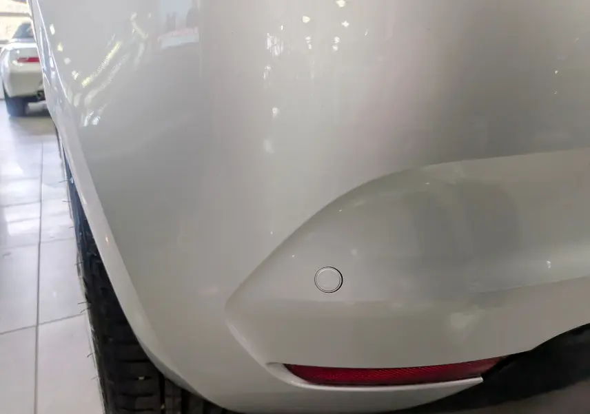 Gros plan sur l'angle arrière droit d'une Renault Clio V gris platine, mettant en valeur le capteur de recul et le feu arrière.