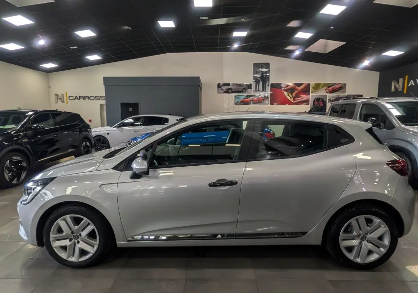 Vue latérale droite d'une Renault Clio V gris platine en intérieur, avec jantes alliage et poignées noires.