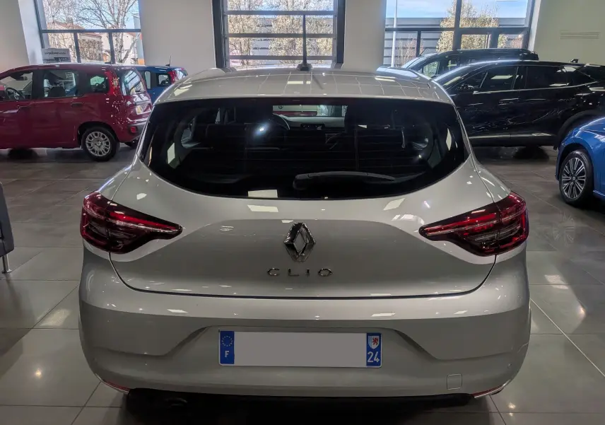 Vue arrière d'une Renault Clio V gris platine 2021 en showroom, avec feux arrière LED et logo central visible.