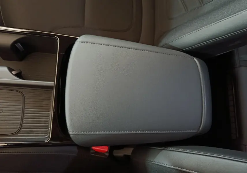 Détail de l'accoudoir central en cuir gris foncé du Hyundai Tucson 2025, avec console de rangement adjacente.