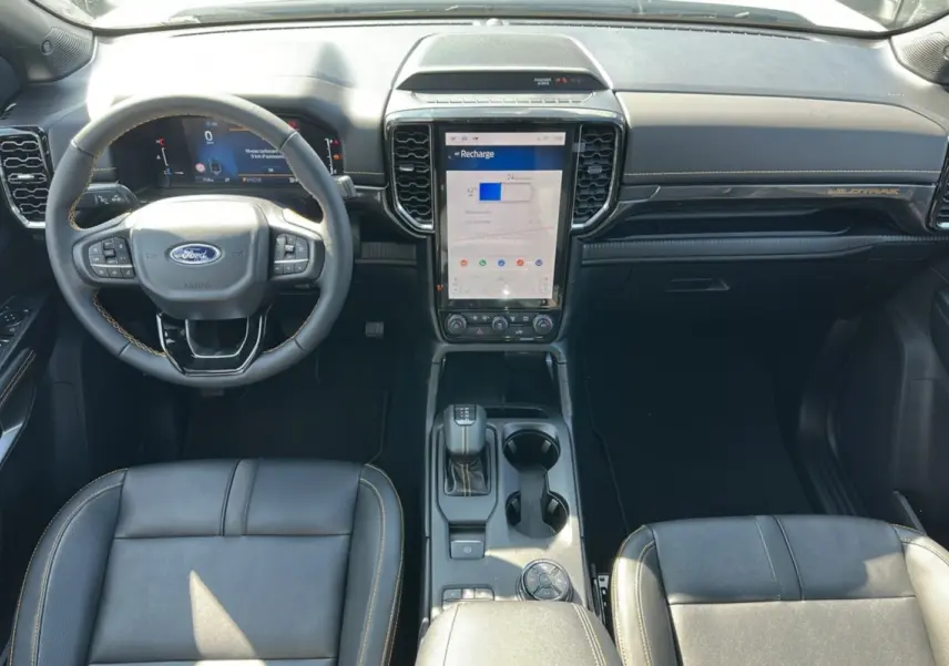 Vue intérieure frontale du Ford Ranger Wildtrak 2026, montrant le volant cuir multifonctions et l’écran tactile central vertical.
