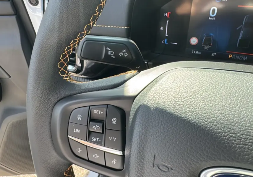 Gros plan sur le volant cuir noir avec surpiqûres orange et commandes multifonctions du Ford Ranger blanc 2026.