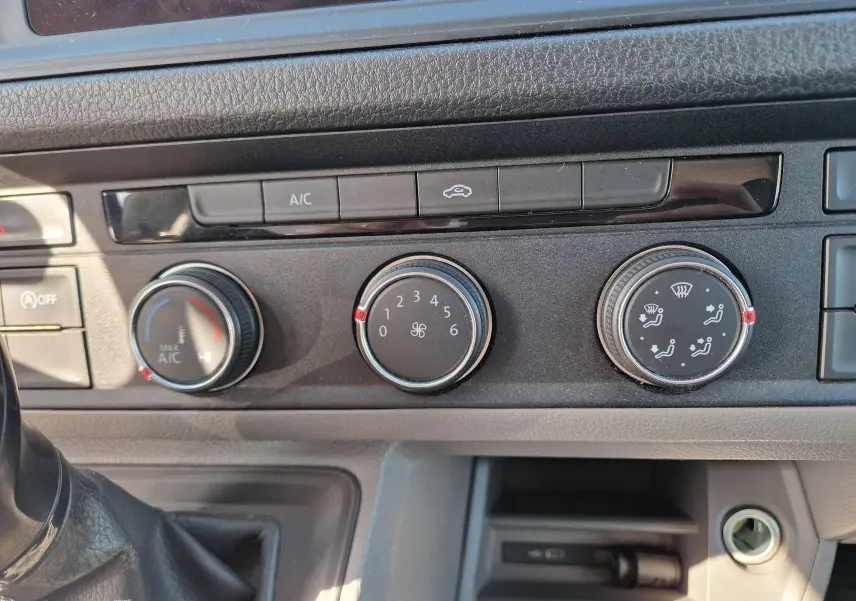 Vue rapprochée des commandes de climatisation du Volkswagen Crafter blanc, avec boutons rotatifs et affichages fonctionnels.