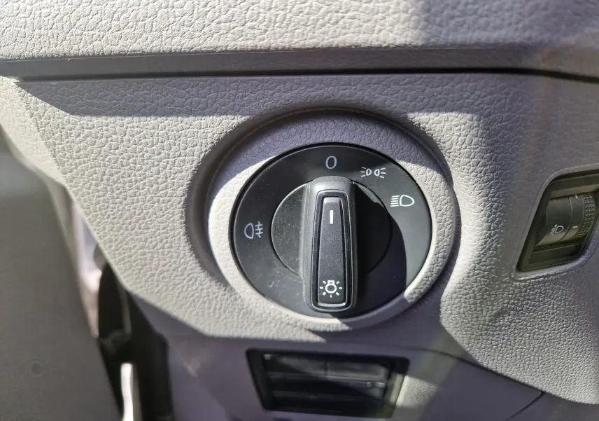 Gros plan sur le bouton de commande des phares dans l'habitacle gris du Volkswagen Crafter blanc de 2021.