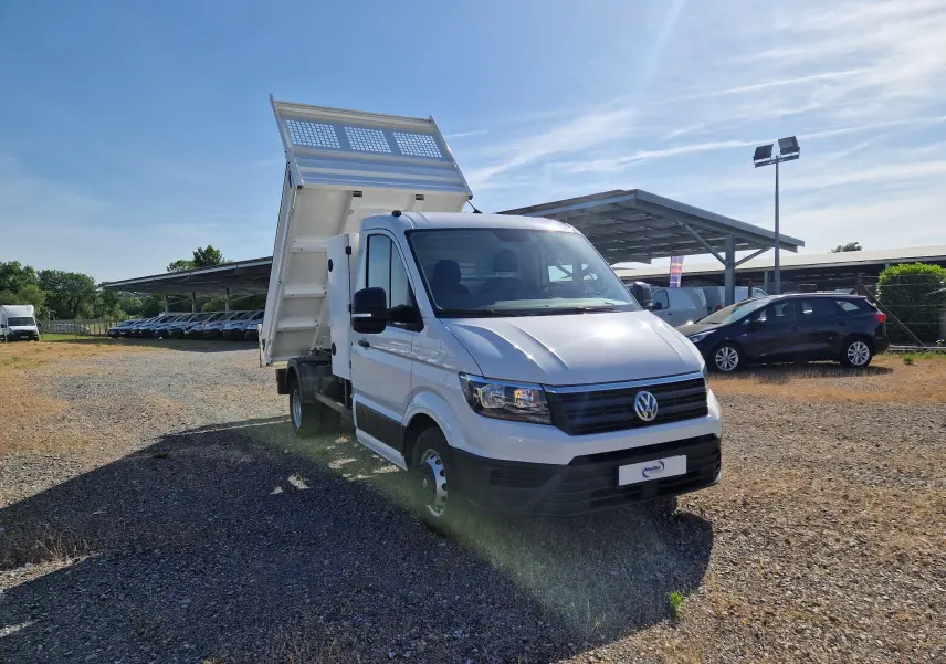 Volkswagen Crafter blanc en 3/4 avant droit avec benne relevée et coffre latéral sur terrain extérieur.