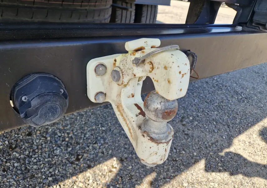Gros plan sur l'attelage blanc rouillé du Volkswagen Crafter Chassis Cabine blanc, avec prise électrique noire à gauche.