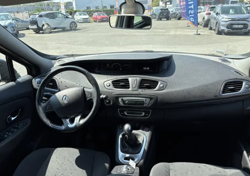 Vue intérieure avant du Renault Scénic beige 2015, volant cuir, tableau de bord avec écran multifonction et boîte manuelle.