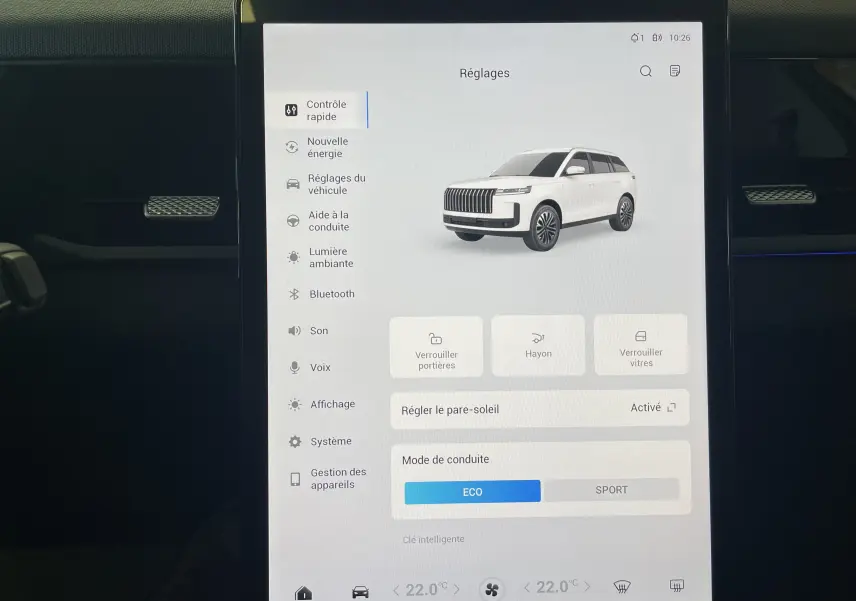 Écran tactile intérieur affichant les réglages du JAECOO J5 en vue 3/4 avant blanche, avec options de conduite et verrouillage.