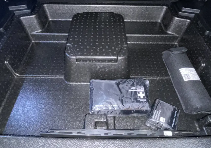 Coffre ouvert du JAECOO J5 2026 en Phantom Grey Metal, vue plongeante sur rangement avec trousse de secours et accessoires.
