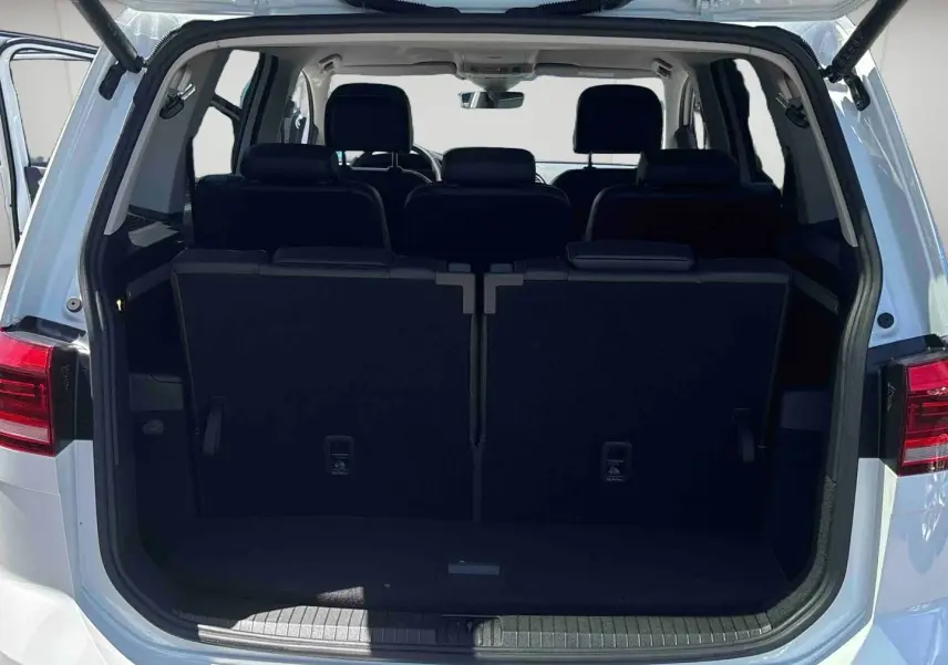 Vue arrière du Volkswagen Touran blanc avec hayon ouvert montrant les sièges arrière et le coffre fermé.