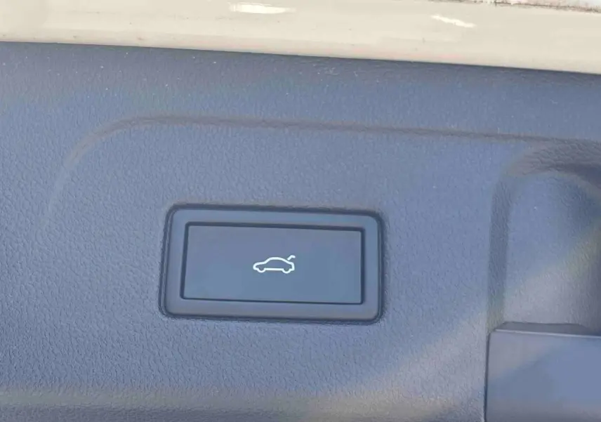 Bouton d'ouverture électrique du hayon sur la garniture intérieure du coffre du Volkswagen Touran blanc.