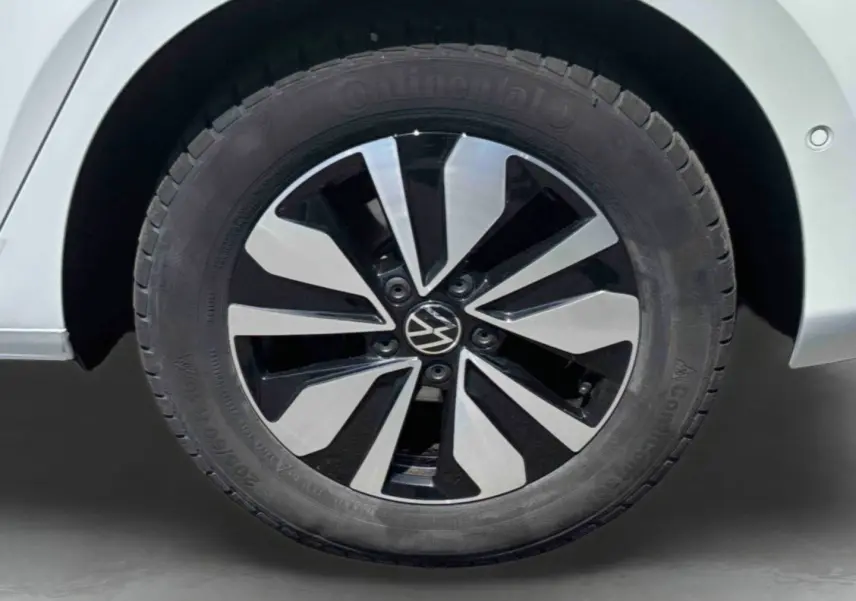 Gros plan sur la jante en alliage bicolore noire et argentée du côté arrière droit d’un Volkswagen Touran blanc.