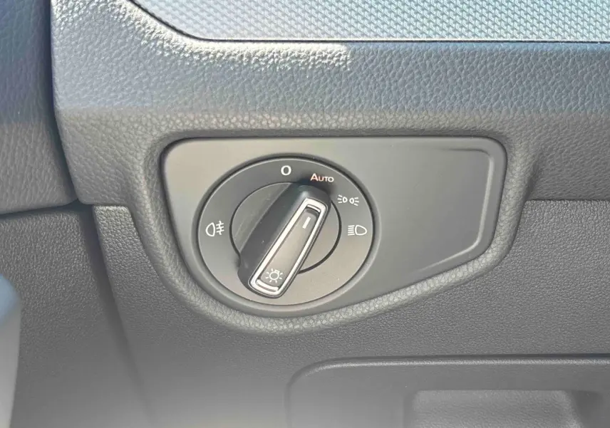 Gros plan sur la commande d'éclairage noire intégrée au tableau de bord du Volkswagen Touran blanc.