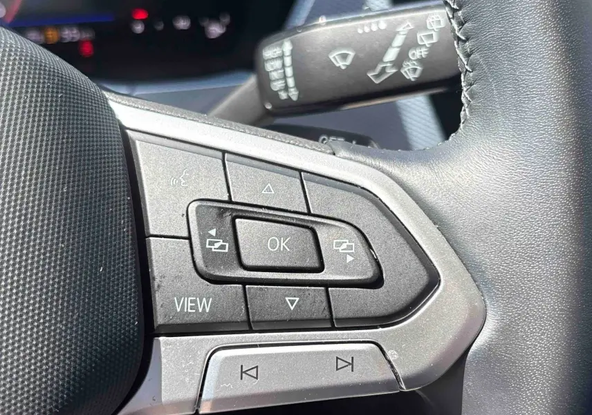 Gros plan sur le volant cuir multifonctions du Volkswagen Touran 2025, boutons de commande visibles côté gauche.