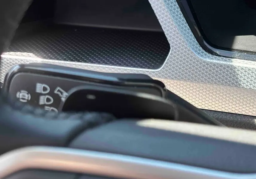 Détail intérieur du Volkswagen Touran 2025 montrant la commande des feux et un insert décoratif argenté.