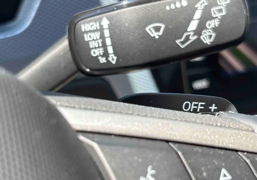 Gros plan sur les commandes de lève-glace et essuie-glace au volant d’un Volkswagen Touran blanc 2025.