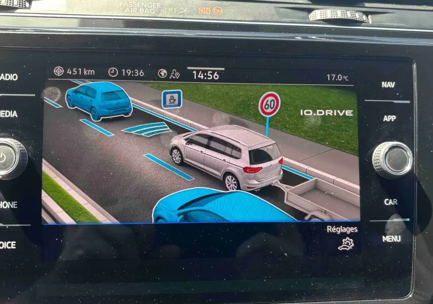 Affichage écran navigation montrant un Volkswagen Touran blanc vu de trois-quarts arrière avec remorque sur route à 60 km/h.