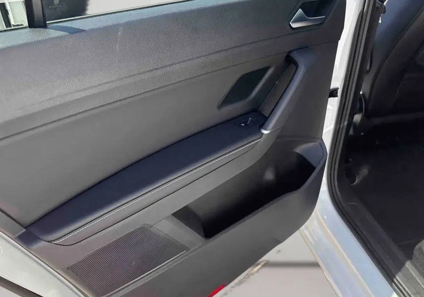 Vue rapprochée de la porte avant gauche ouverte du Volkswagen Touran blanc, montrant la garniture intérieure noire et la commande de fenêtre.