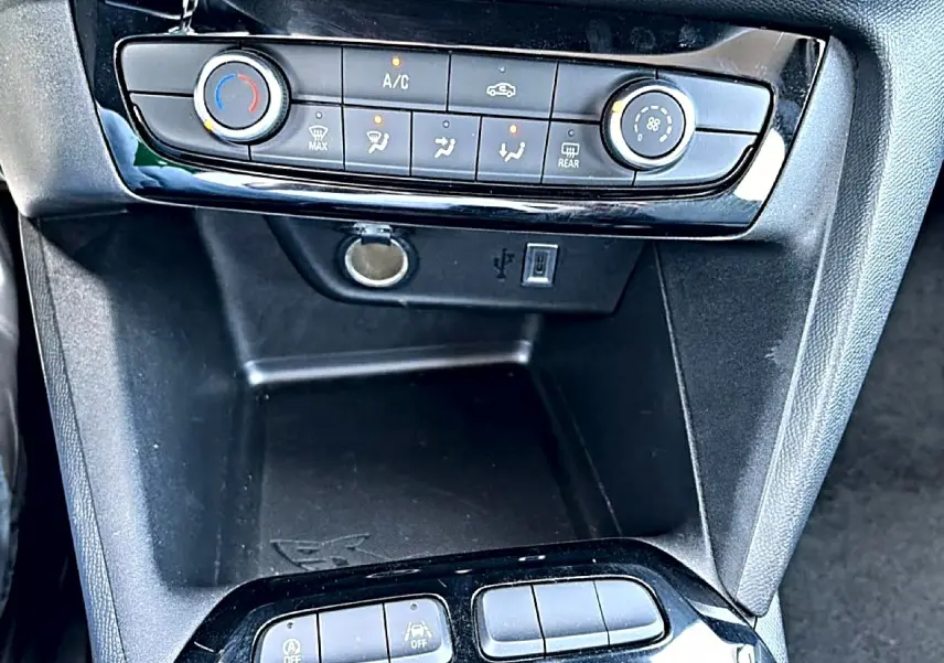 Détail du tableau de bord noir de l’Opel Corsa 1.2 turbo 100 édition avec commandes clim et prise USB visible.
