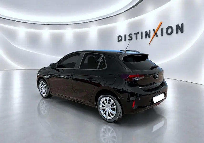 Opel Corsa 1.2 turbo noir vue 3/4 arrière droit dans un showroom lumineux avec logo Distinxion en arrière-plan.