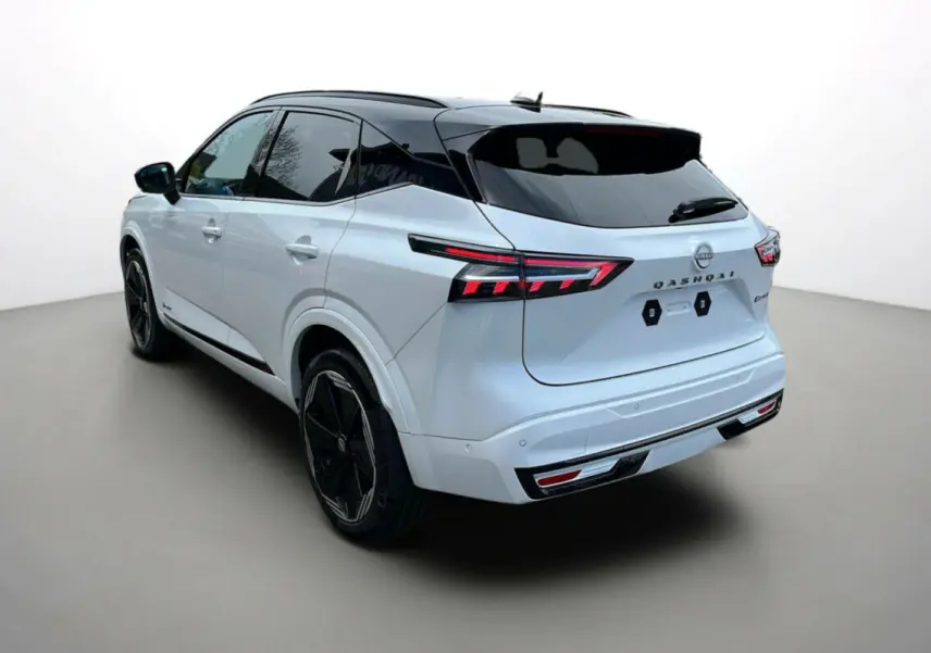 Vue 3/4 arrière gauche du Nissan Qashqai blanc nacré avec toit noir et jantes noires 20 pouces, feux arrière LED allumés.