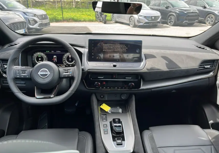 Vue intérieure avant du Nissan Qashqai E-POWER 205 N-DESIGN avec tableau de bord moderne et volant cuir multifonctions.