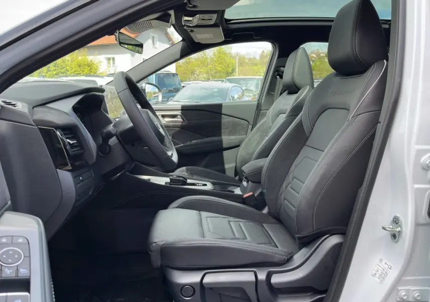 Vue intérieure côté conducteur du Nissan Qashqai E-POWER 205 N-Design avec sièges cuir alcantara noirs et toit panoramique visible.