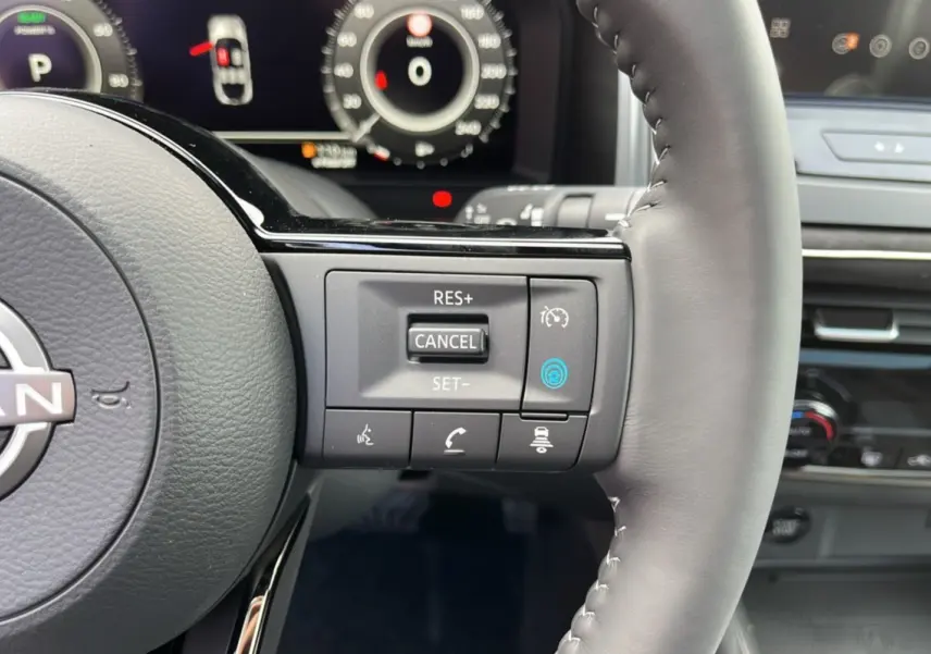 Gros plan sur le volant cuir multifonctions du Nissan Qashqai E-POWER 2026 avec commandes de régulateur et tableau de bord numérique.