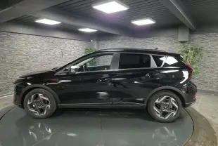 Vue de profil côté gauche d'une Hyundai Bayon noire métallisée 2025 dans un showroom avec jantes alliage 17 pouces.