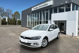 Volkswagen Polo Business blanche vue en 3/4 avant droit devant un bâtiment de concession automobile.