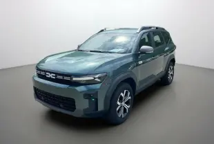 SUV Dacia Bigster vert cèdre en 3/4 avant droit, avec barres de toit et jantes alu 17 pouces visibles.
