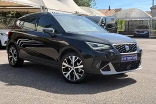 SEAT Arona noir vue 3/4 avant droit, avec jantes alliage et calandre distinctive sous un ciel ensoleillé.