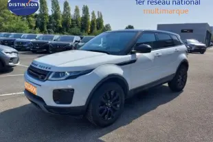 Vue 3/4 avant d'un Range Rover Evoque blanc 2018 avec détails noirs, garé sur un parking extérieur multimarque.