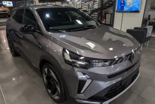 Renault Symbioz E-Tech gris Cassiopé en 3/4 avant droit, avec phares LED et jantes bicolores en showroom.