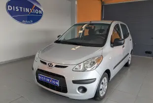 Vue 3/4 avant droite d'une Hyundai i10 gris clair de 2010, compacte avec cinq portes et rétroviseurs noirs.