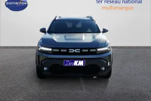 Vue frontale d'un Dacia Duster TCE MHEV 140ch Journey gris schiste métal avec calandre distinctive et feux LED allumés.