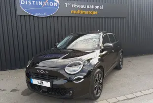 Vue 3/4 avant droite d'une FIAT 600 noire brillante, avec jantes noires et calandre distinctive, stationnée devant un mur gris.