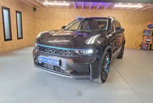 Vue 3/4 avant du SUV LYNK & CO 01 noir avec détails bleus sur la calandre et jantes dans un garage éclairé.