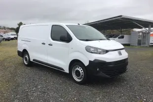 Fiat Scudo Fourgon blanc vu en 3/4 avant droit, avec pare-chocs noirs et jantes acier, sur parking extérieur.