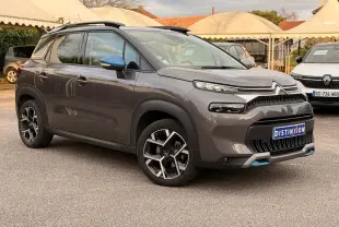 Vue 3/4 avant droit d'un Citroën C3 Aircross gris platinium avec jantes noires et détails bleus sur le bouclier avant.
